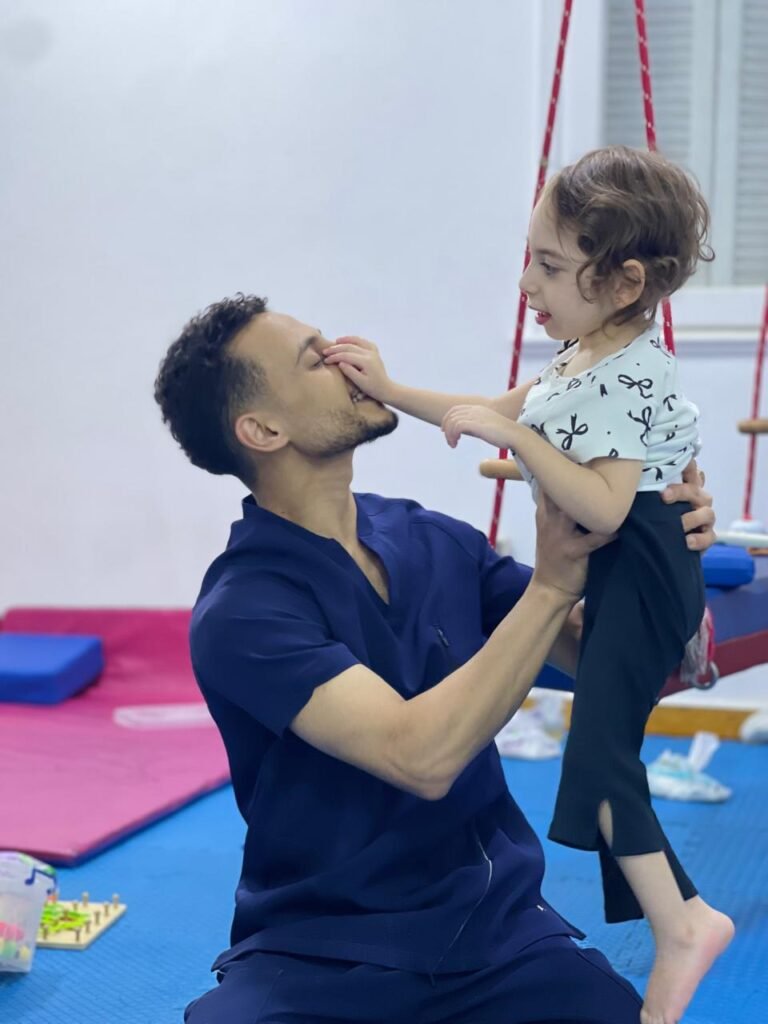 أخصائي يساعد طفلة على الوقوف أثناء جلسة تأهيل