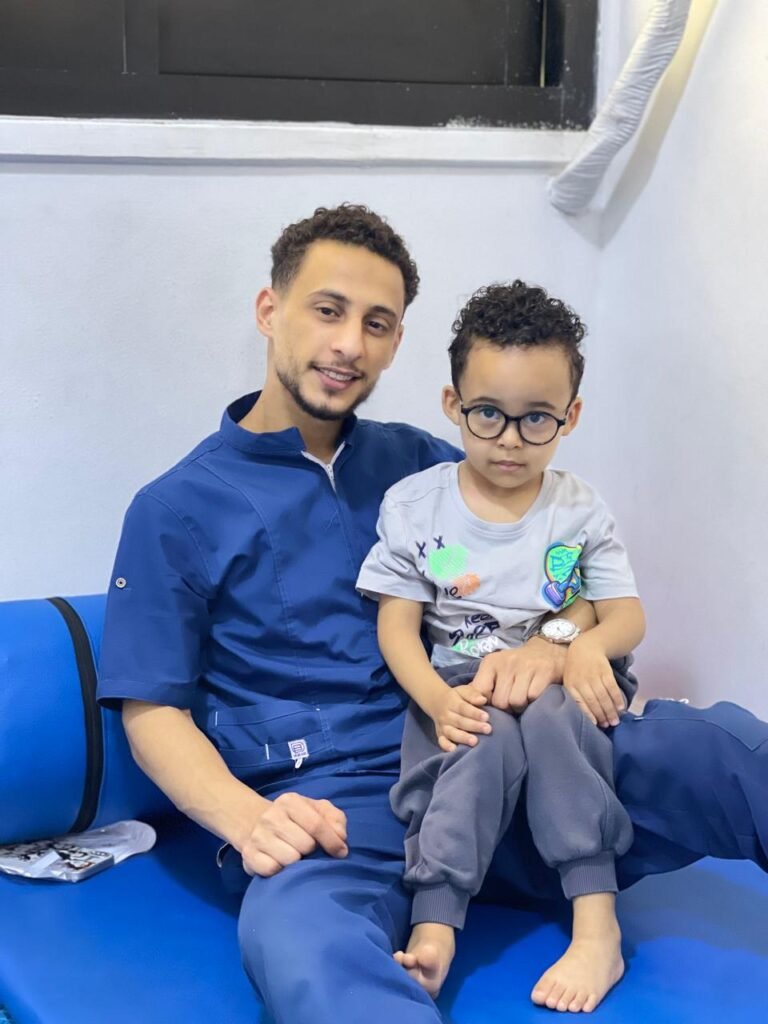 أخصائي يجلس مع طفل يرتدي نظارة داخل المركز
