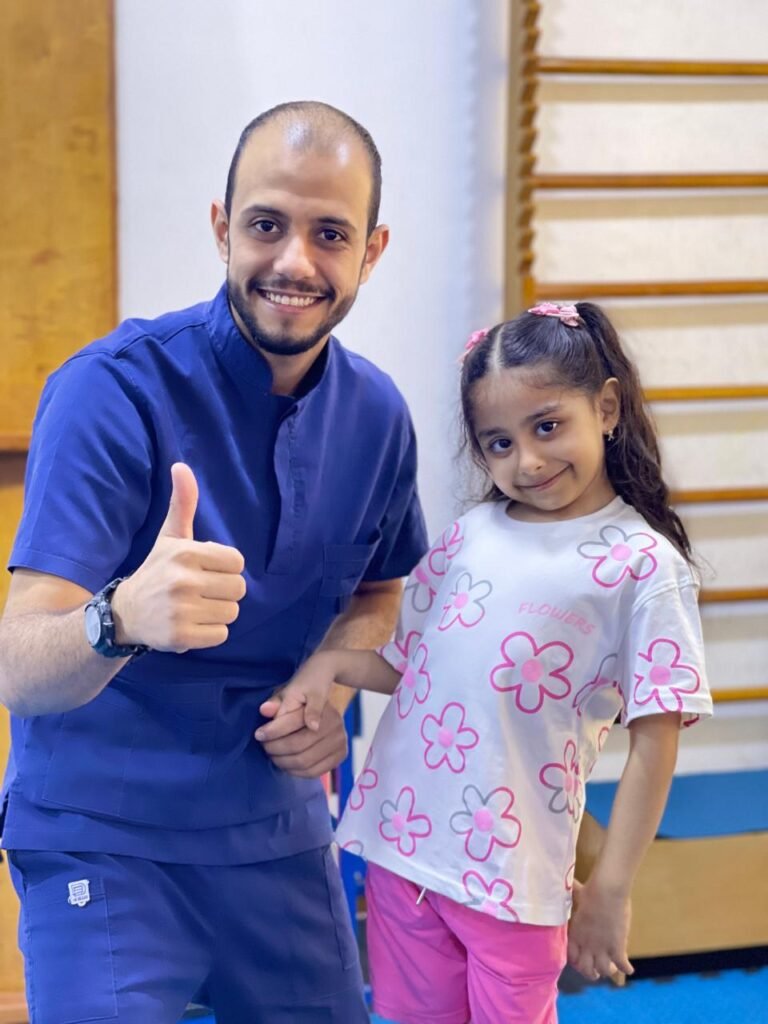 أخصائي وطفلة يبتسمان داخل مساحة التأهيل